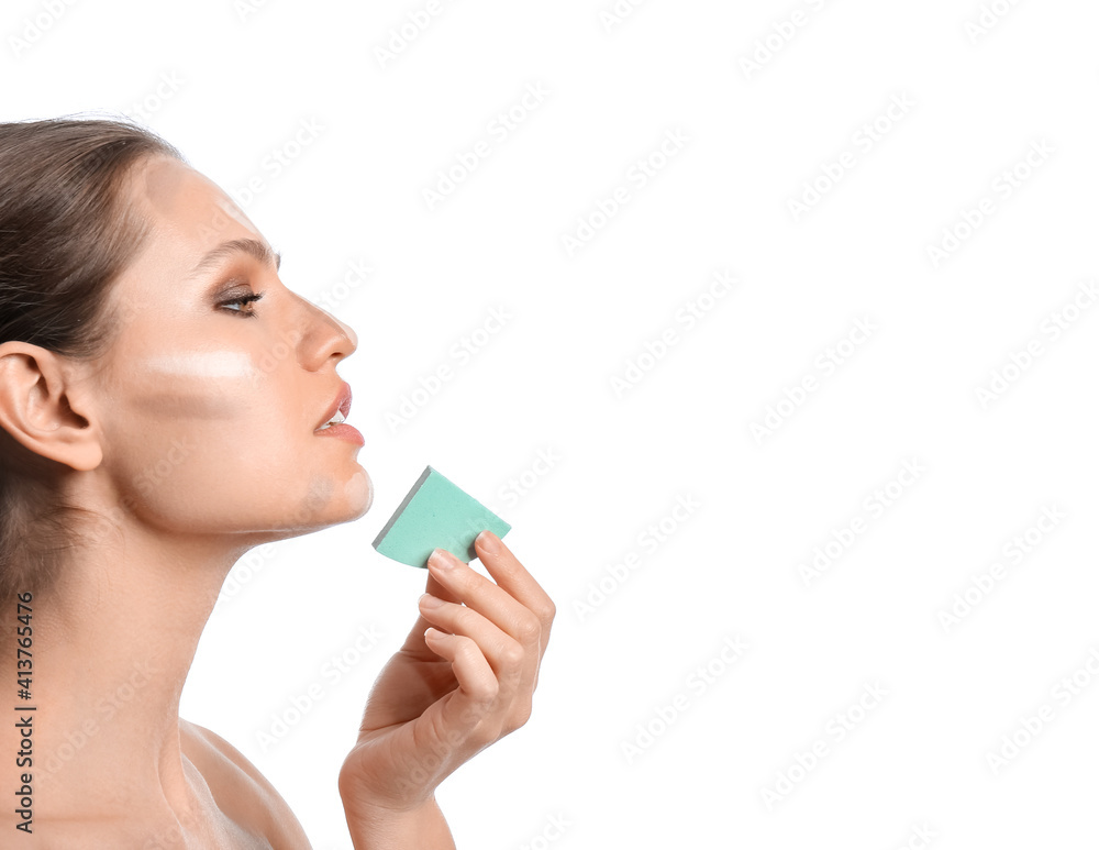 Beautiful young woman applying contouring makeup against white background