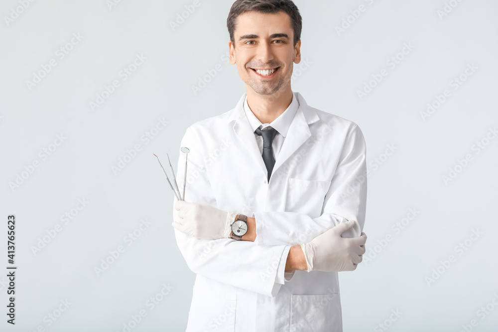 Male dentist on light background