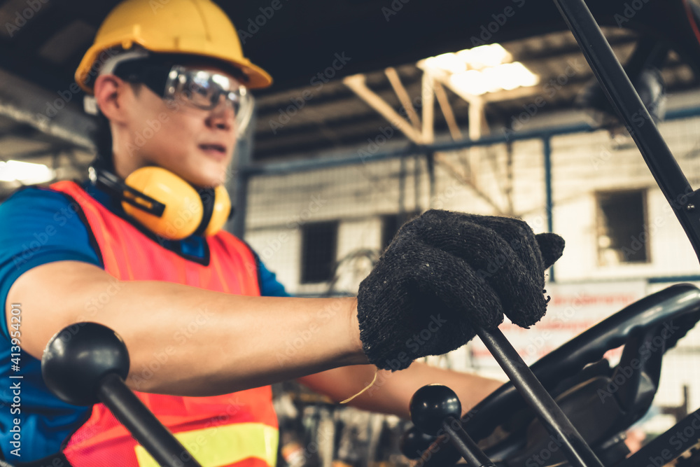 Skillful worker drives forklift in the factory . Industrial people and manufacturing labor concept .