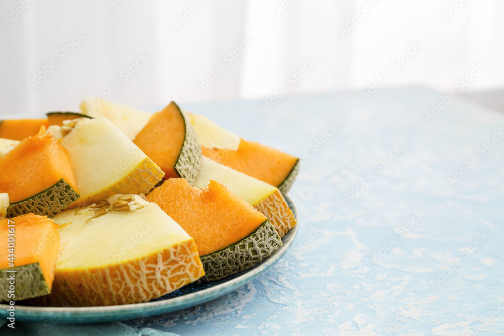 Plate with sweet cut melon on color background