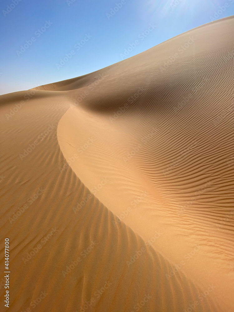 Simple abstract desert scenery with sand dunes and blue sky. Liwa desert, Abu Dhabi, UAE.