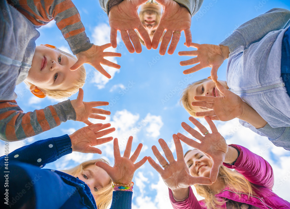 A friendly large family makes a circle shape out of the palms of their hands.