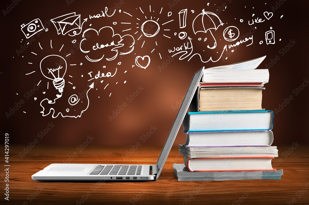 Stack of books with modern laptop on table