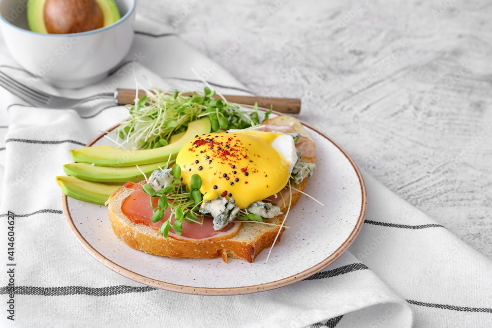 Tasty sandwich with florentine egg, bacon and avocado on light background