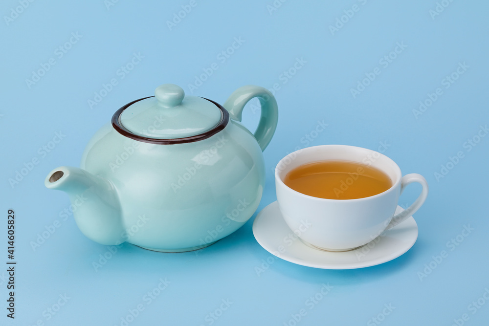 Stylish teapot and cup of tea on color background