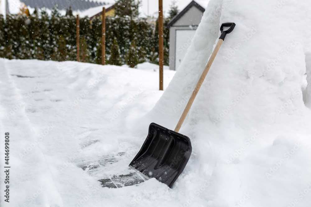 用铲子清除房子前面车道的积雪