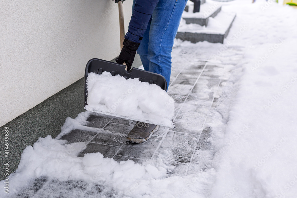 用铲子清除房子前面车道的积雪