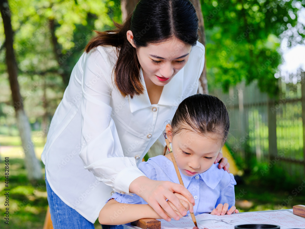 Happy mother and daughter write calligraphy outdoors