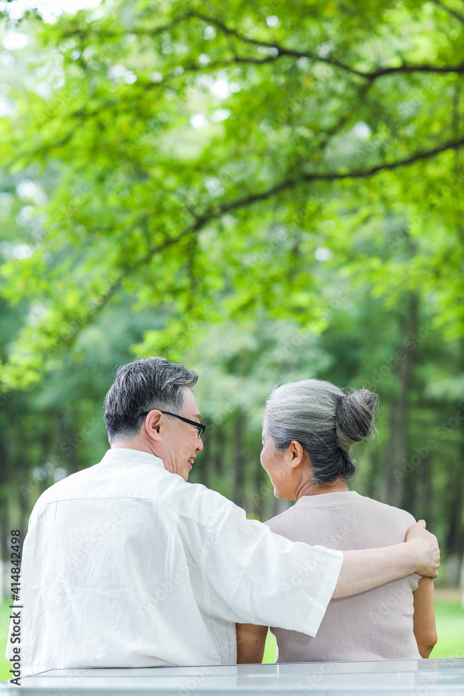 Happy old couple sitting on chairs in outdoor park