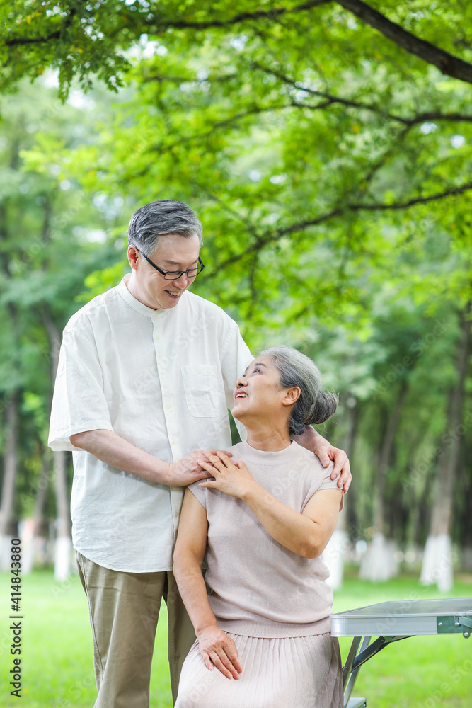 快乐的老夫妇坐在户外公园的椅子上