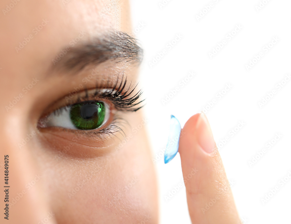 Young woman putting in contact lenses on white background, closeup