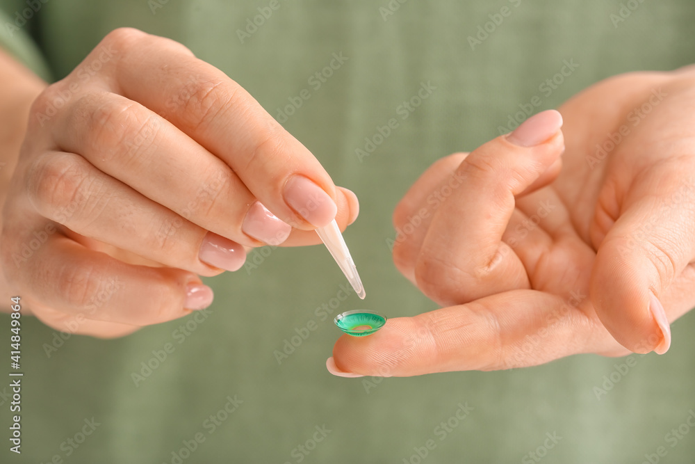 Female hands with tweezers and contact lens, closeup