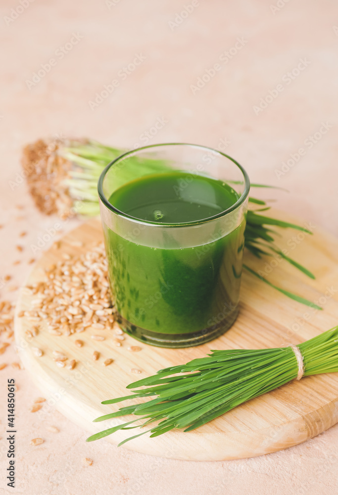 Glass with fresh wheatgrass juice on light background