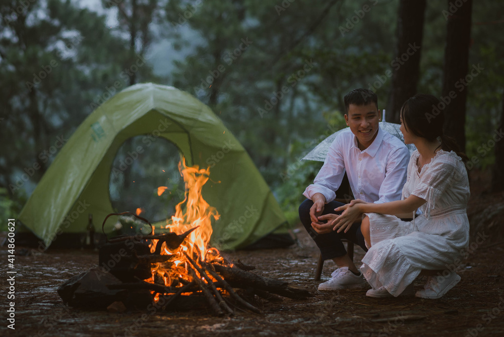 一对年轻的亚洲夫妇坐在篝火旁