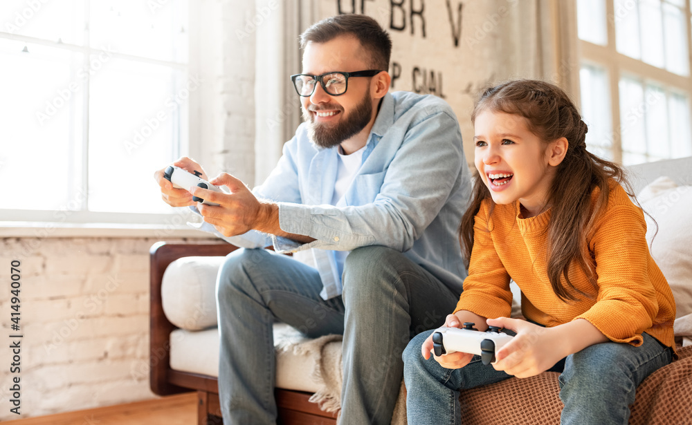 father and daughter laugh and play video games together using a video game console