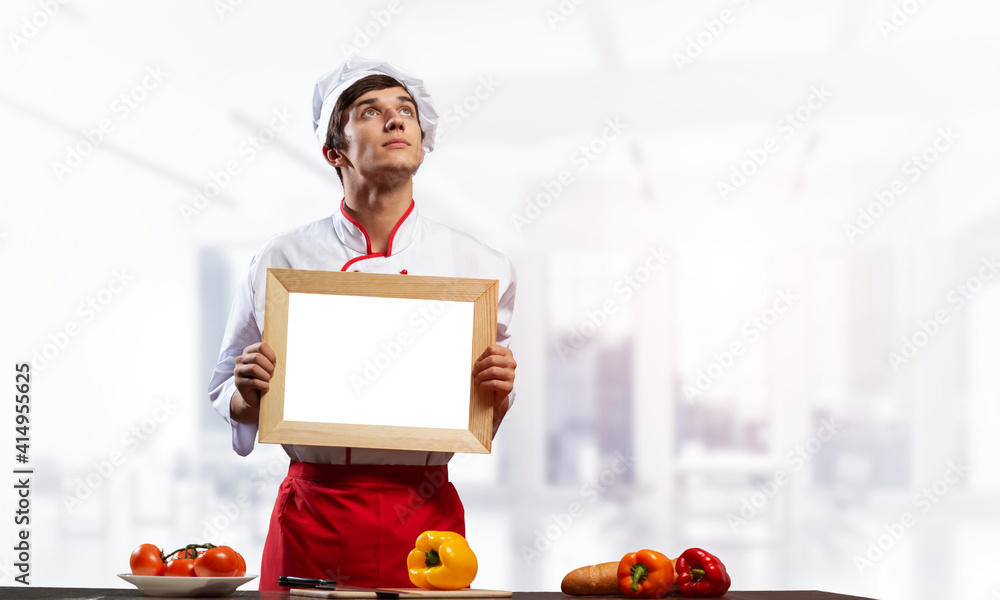 Young male chef standing near cooking table