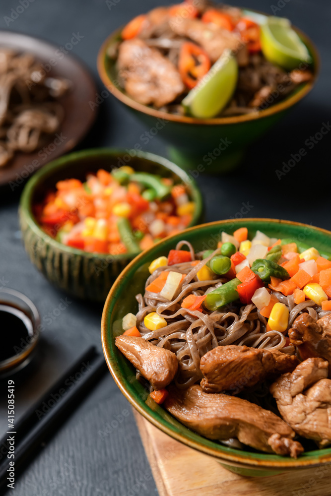 深色背景下的碗里有美味的荞麦面、蔬菜和肉，特写