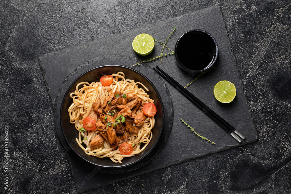 Plate with tasty noodles and meat on dark background