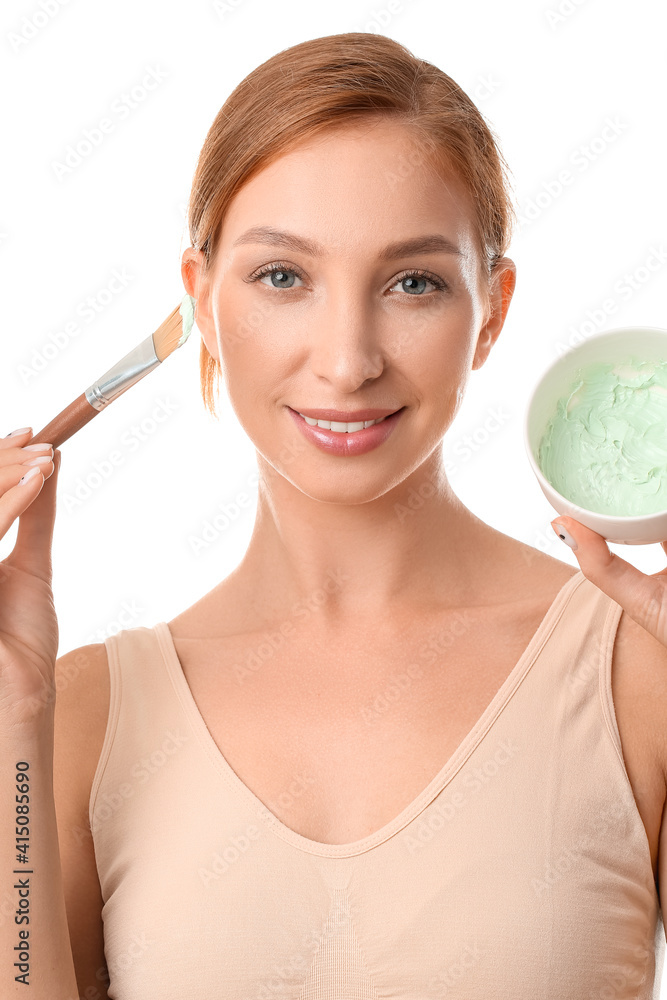 Beautiful young woman with facial cream and brush on white background, closeup