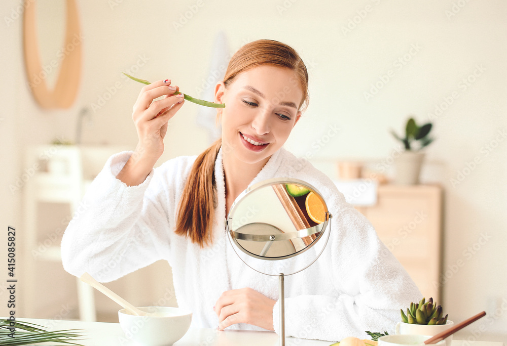 Beautiful young woman with aloe vera in bathroom