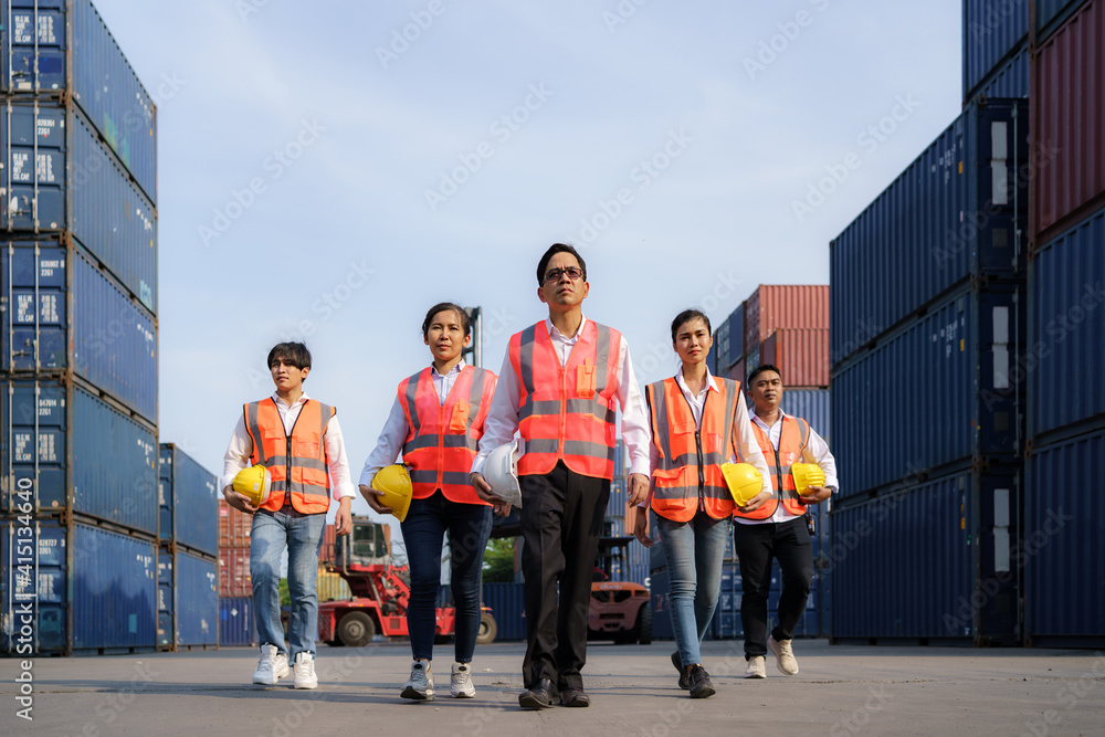 Asian foreman walking with four workers employee team after finishing work on the container depot te