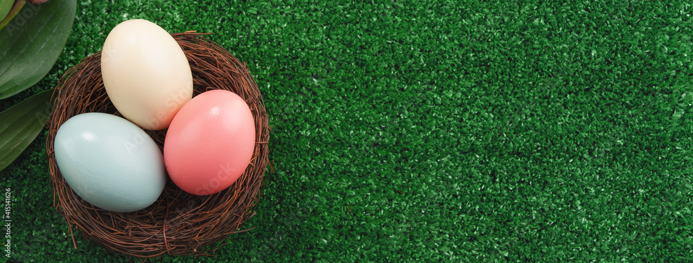 Colorful Easter eggs in the nest on a lawn with pink Double Lily flower.