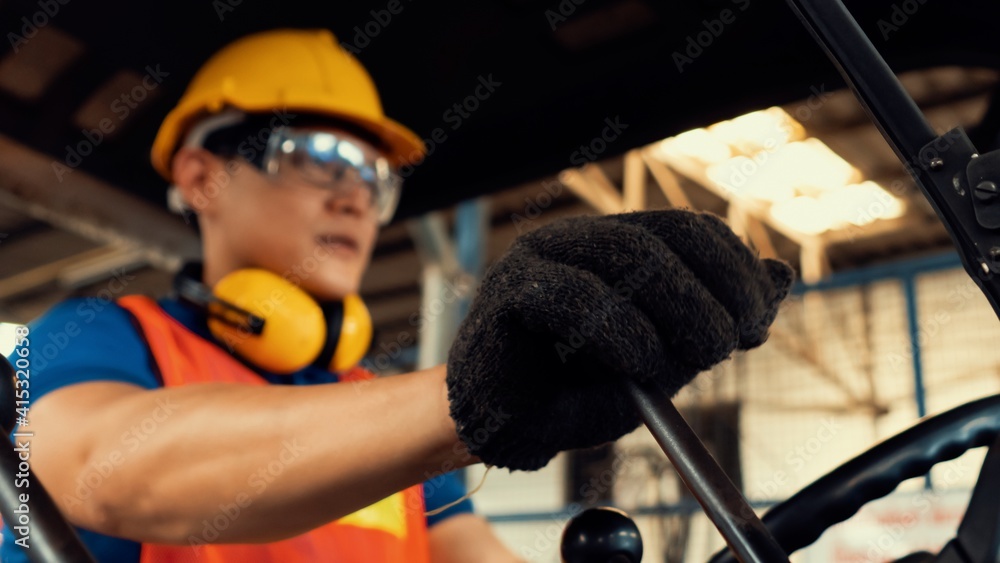 Skillful worker drives forklift in the factory . Industrial people and manufacturing labor concept .