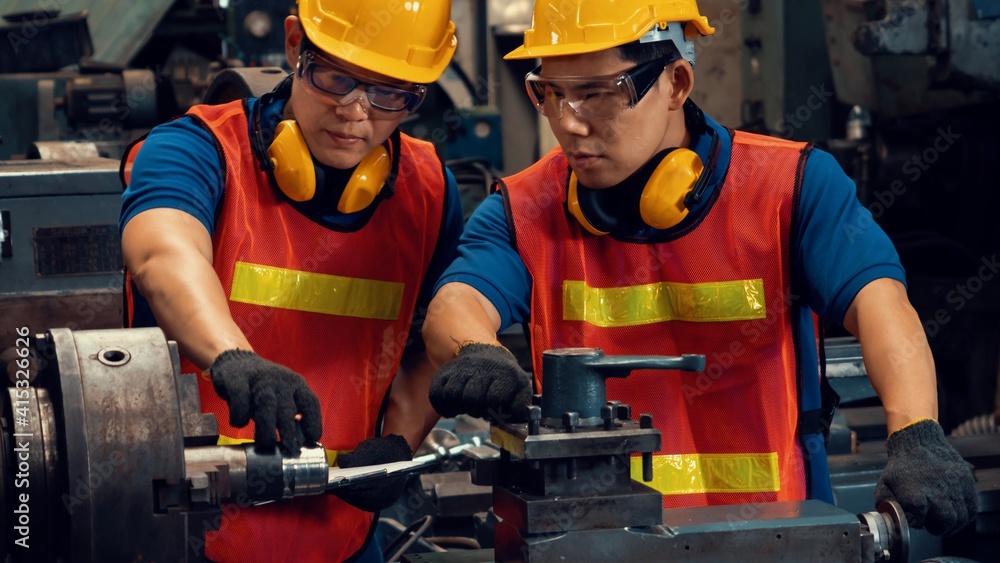 Group of skillful factory workers using machine equipment in workshop . Industry and engineering peo