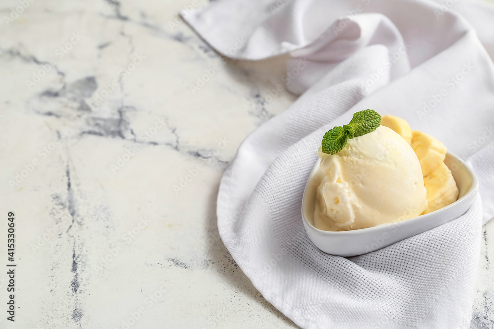 Bowl with banana ice-cream and mint on light background