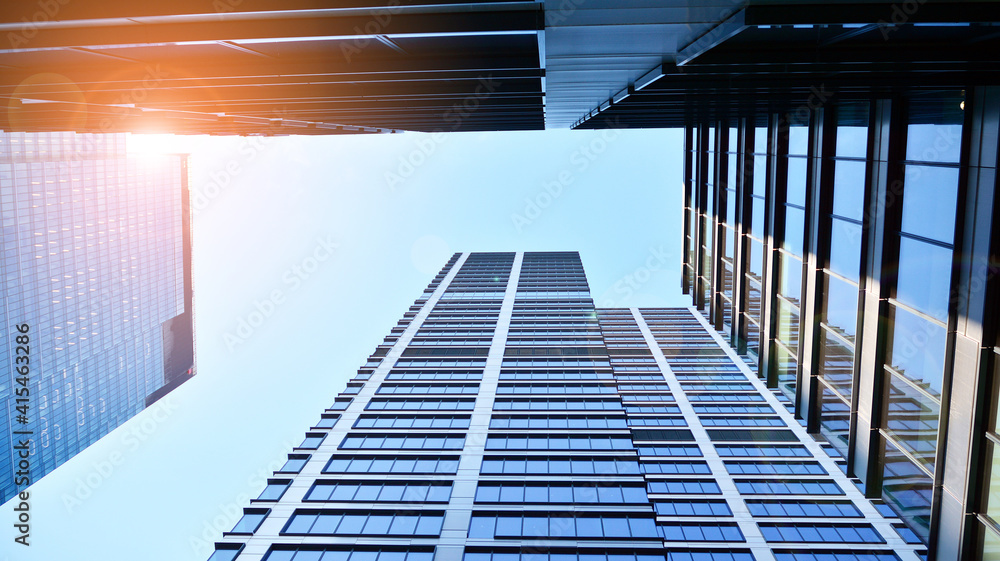 Bottom view of modern skyscrapers in business district against blue sky. Looking up at business buil