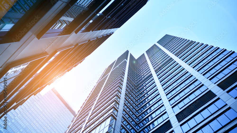 Bottom view of modern skyscrapers in business district against blue sky. Looking up at business buil