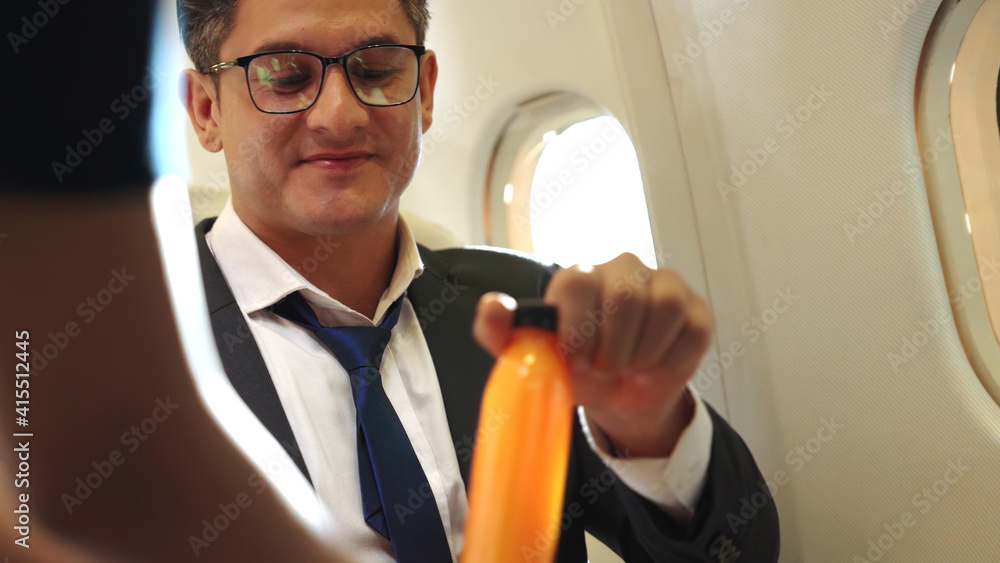 Businessman have orange juice served by an air hostess in airplane . Business trip travel concept .