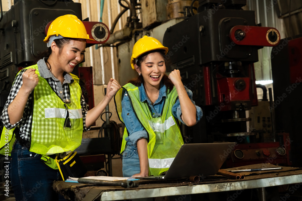 Two factory job worker celebrate success together in the manufacturing workshop or warehouse . Indus