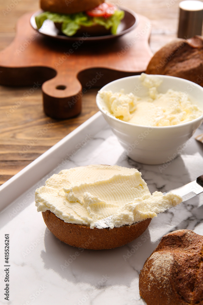 Bun with tasty cream cheese on wooden background