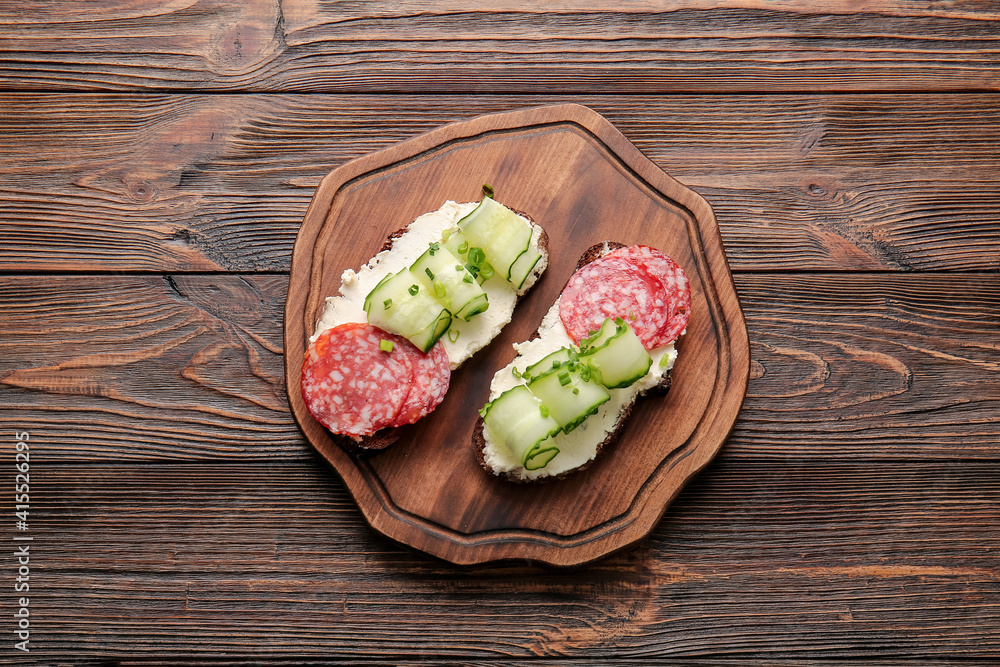 Sandwiches with tasty cream cheese on wooden background