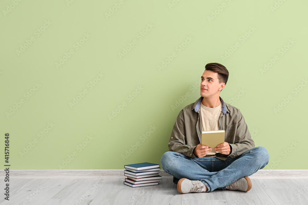 Young man with books near color wall