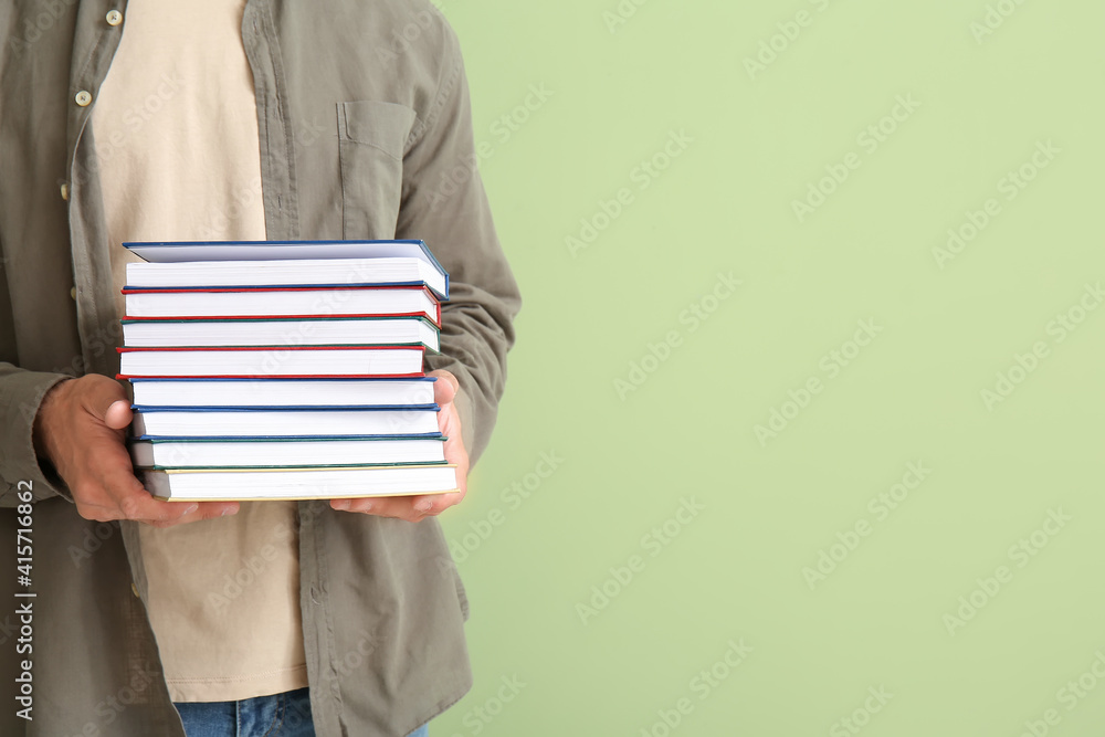 Young man with books on color background