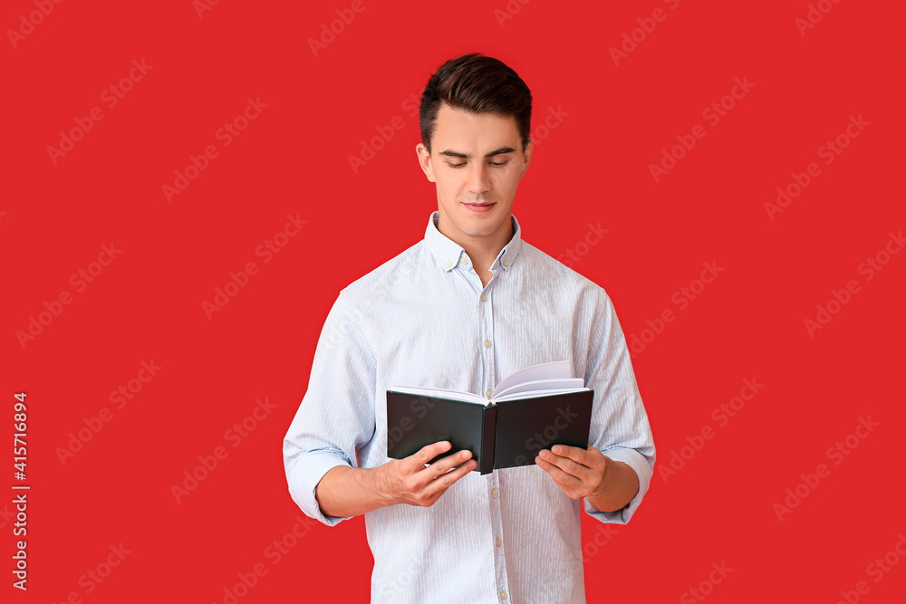 Young man reading book on color background