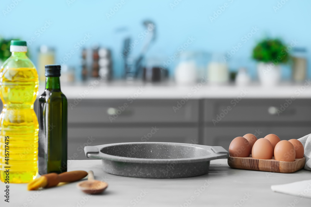 Eggs, oil and baking sheet on table in modern kitchen