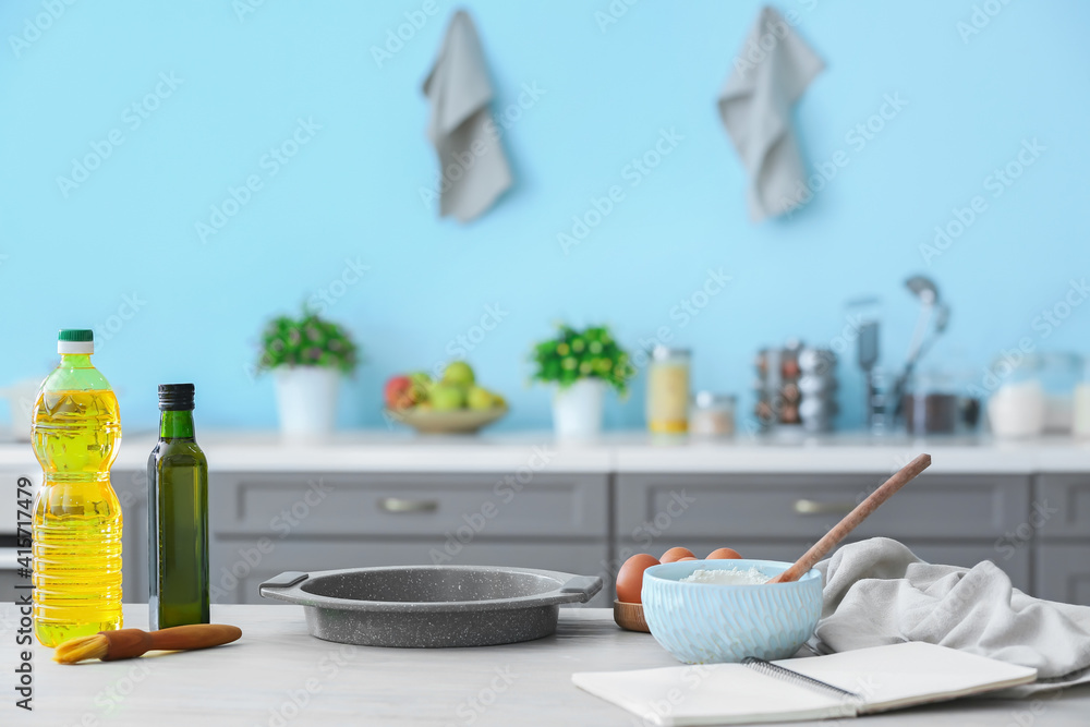 Bowl with flour, oil and baking sheet on table in modern kitchen