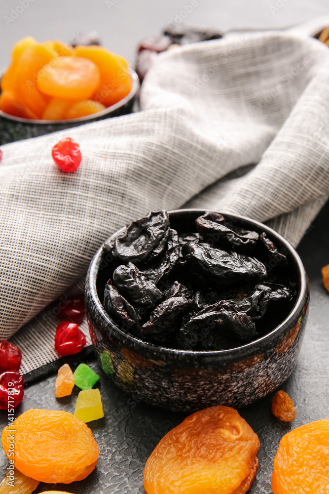 Bowl with dried prunes on dark background