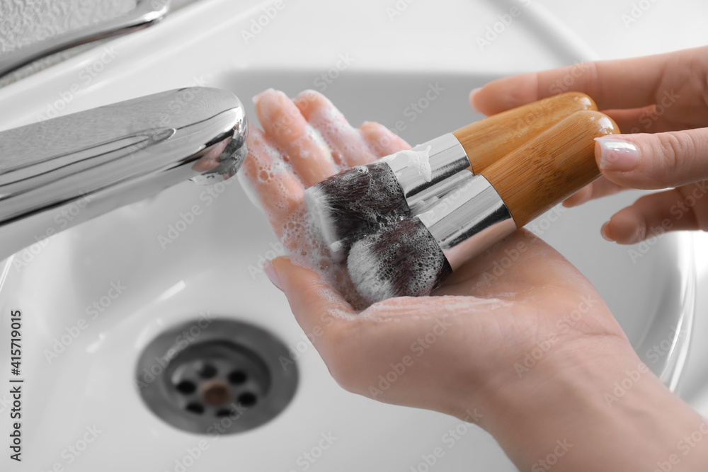 Woman washing makeup brushes under water