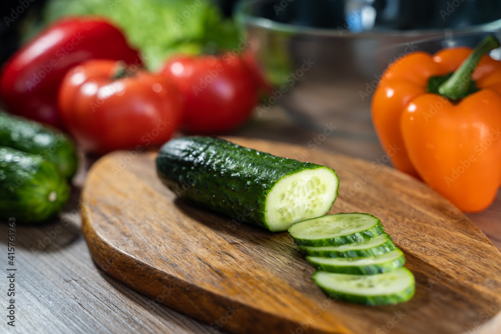 Woman cutting fresh cucumber at table, closeup