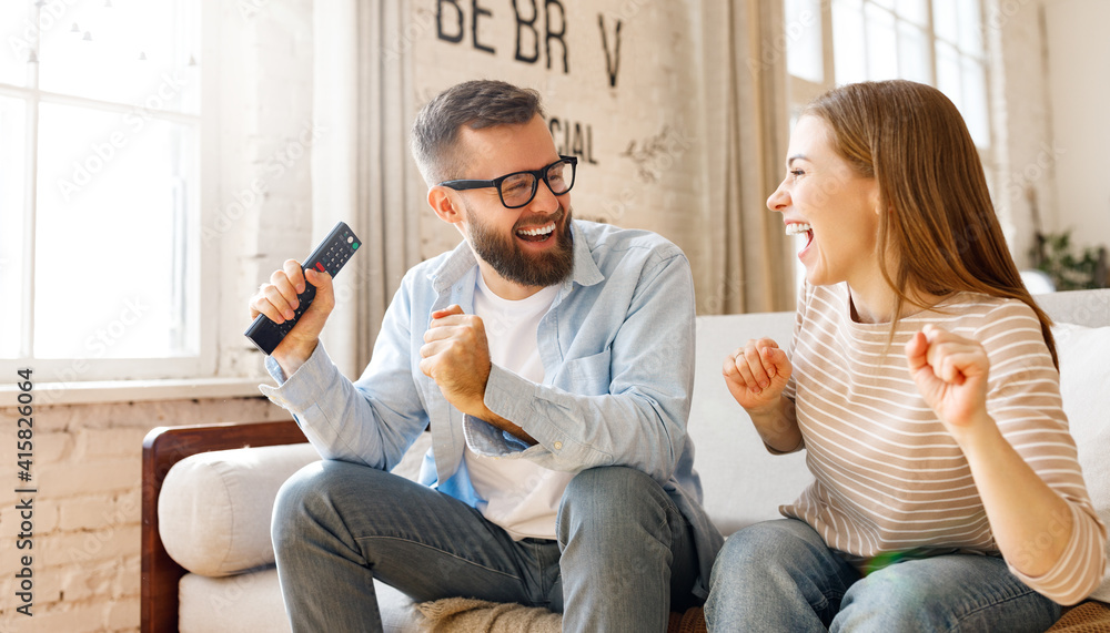 Happy couple celebrating victory while watching TV