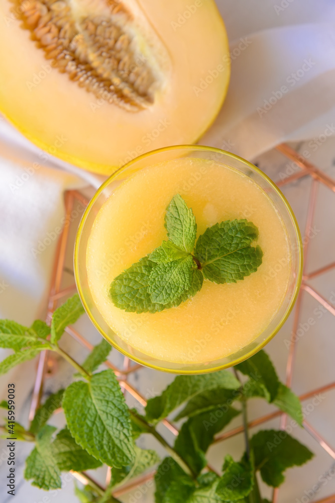 Glass with melon smoothie on light background