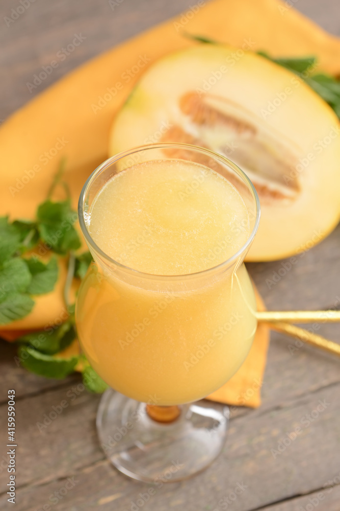 Glass with melon smoothie on wooden background