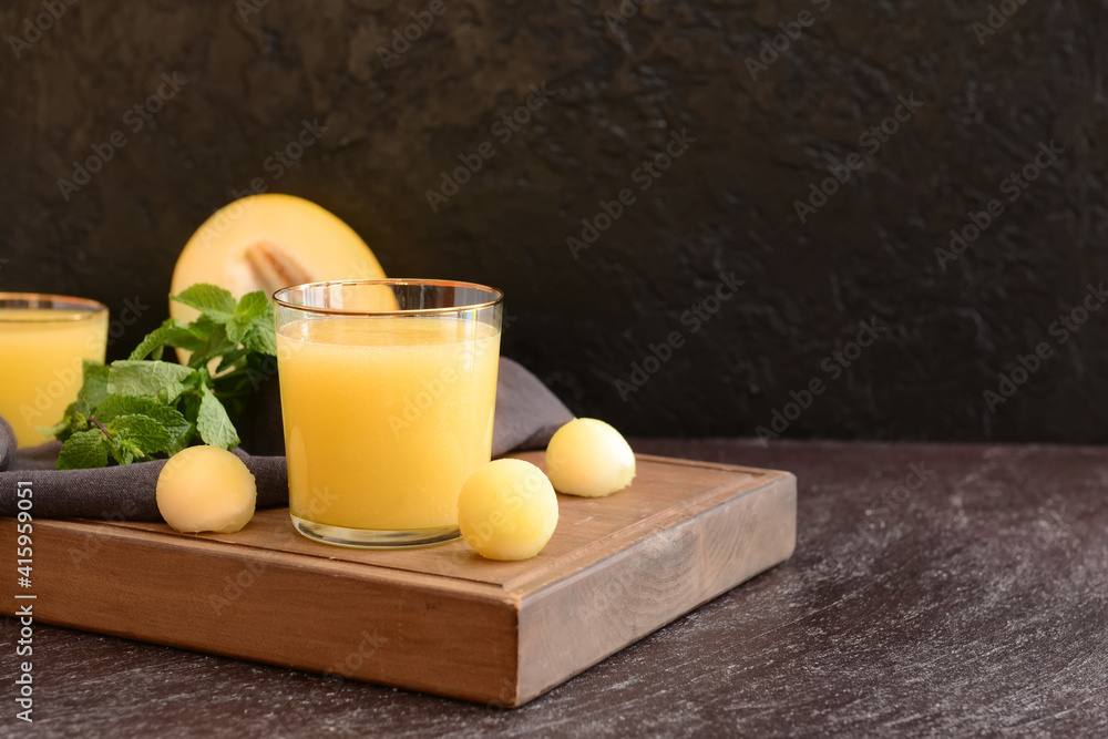 Glass with melon smoothie on dark wooden background