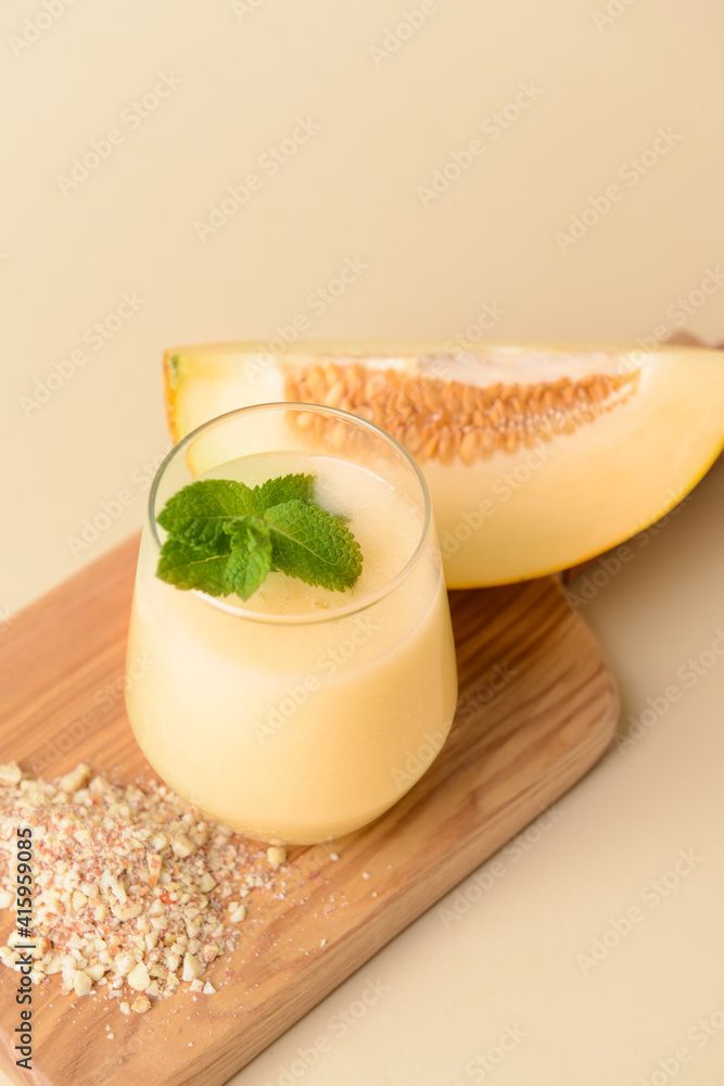 Glass with melon smoothie on color background