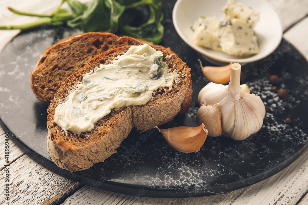 Board with slices of fresh bread, garlic butter and ingredients on light wooden background, closeup