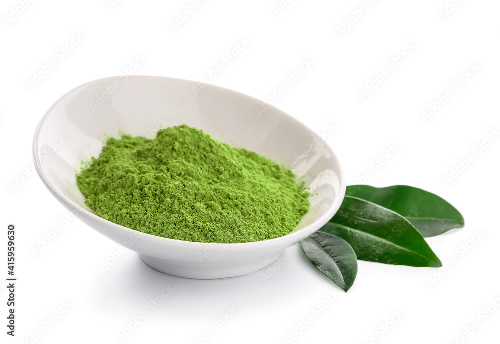 Bowl with powdered matcha tea and fresh leaves on white background